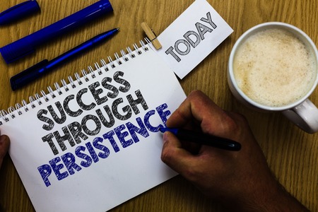 Text sign showing Success Through Persistence. Conceptual photo never give up in order to reach achieve dreams Man holding marker notebook clothespin reminder wooden table cup coffeeの写真素材