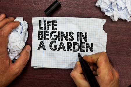 Conceptual hand writing showing Life Begins In A Garden. Business photo text Agriculture Plants growing loving for gardening Hand hold pen sketch word on torn page woody deck hand paper ballの写真素材