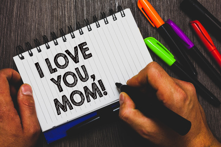 Word writing text I Love You, Mom. Business concept for Loving message emotional feelings affection warm declaration Hand holding pen and paper sketch words near lie some pen on woody deskの写真素材