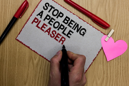 Text sign showing Stop Being A People Pleaser. Conceptual photo Do what you like not things other people want Written sticky note clip pinch heart hand hold marker red pen on wooden deskの写真素材
