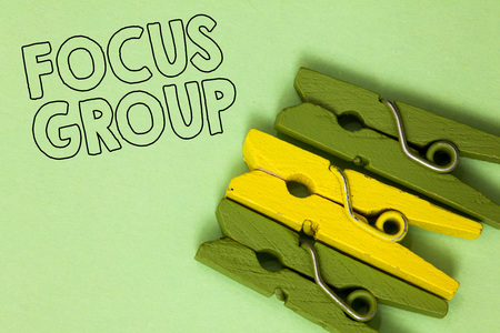 Text sign showing Focus Group. Conceptual photo people assembled to participate in discussion about something Three green yellow vintage clothespins clear background Holding thingsの写真素材