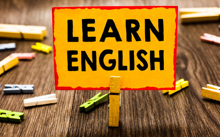 Conceptual hand writing showing Learn English. Business photo showcasing Universal Language Easy Communication and Understand Clothespin holding orange paper note clothespin wooden floorの写真素材