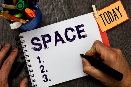 Handwriting text Space. Concept meaning continuous area or expanse which is free available unoccupied Man holding marker notebook clothespin hold reminder cup markers wood tableの写真素材