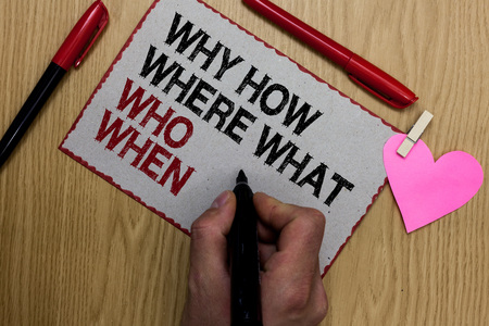 Text sign showing Why How Where What Who When. Conceptual photo Questions to find solutions Query Asking Written sticky note clip pinch heart hand hold marker red pen on wooden deskの写真素材