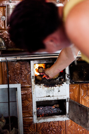Defocused view of a woman starting a fire in a chimney. The housewife adding some woods to sustain the burning. Typical source of heat for cooking. Countryside lifestyle ideaの写真素材