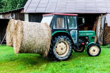 BIRMINGHAM, UK - March 2018 Mini Truck with Two Bales of Haystack Attach at Rear End. Open Warehouse Storing Harvested Hays and Chopped Woods. Fresh Green Meadows Covering the Landのeditorial素材