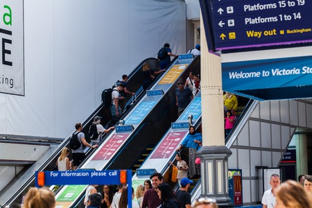 BIRMINGHAM, UK - March 2018 People Carrying their Bags and Luggages inside the London Victoria Train Station. Commuters on Escalators Following the Rules of Stand Right and Walk leftのeditorial素材