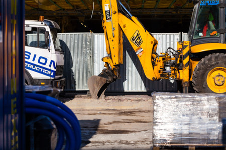 BIRMINGHAM, UK - March 2018 Hoe Heavy Equipment Scooping and Scraping Soil. Metal Plate Fence...