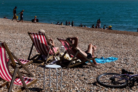 Brighton, UK - June 2018 Couple Relaxing on Wood Adjustable Recliner under the Sun. Family and Group Enjoying Blue Water and Sunshine. Deck Chairs on Pebbled Shore Facing the Oceanのeditorial素材