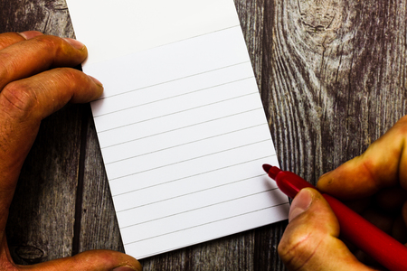 Design business concept Empty template copy space text for Ad website isolated. analysis Hand Holding Marker Pen Writing on Blank Lined Notepad Wood Surfaceの写真素材