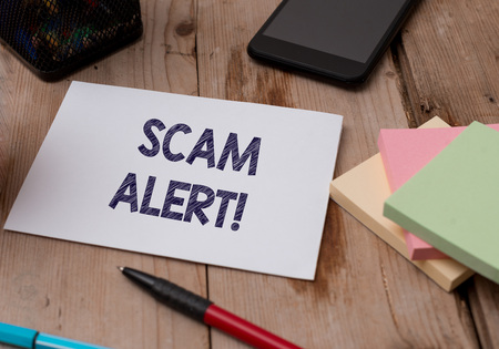 Word writing text Scam Alert. Business photo showcasing fraudulently obtain money from victim by persuading him Top view wooden table stationary paper tablet pen colored stick pad notesの写真素材