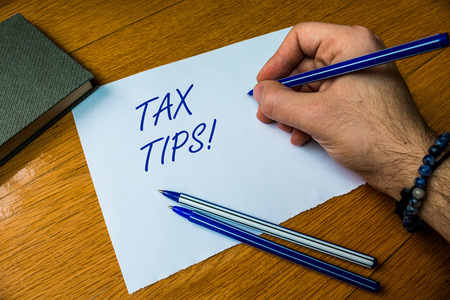 Handwriting text writing Tax Tips. Conceptual photo compulsory contribution to state revenue levied by government Top vie male handwriting wooden desk electronic device Writing down projectの写真素材
