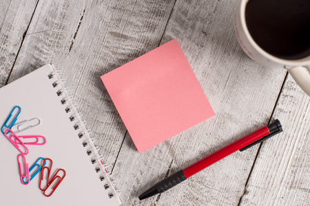 Stationary placed next to a cup of black coffee above the wooden tableの写真素材