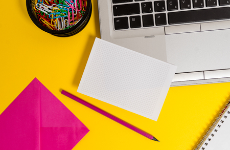 Laptop pencil sheet clips container spiral envelope colored backgroundの写真素材