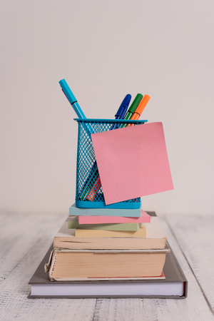 Stacked books pens metal holder sticky note lying vintage old wooden tableの写真素材