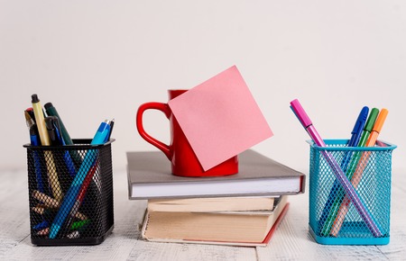 Coffee cup blank sticky note stacked books pen metal holders wooden tableの写真素材