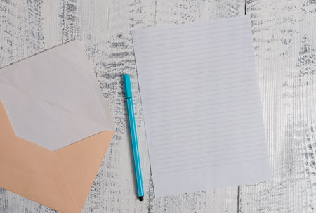 Open colored envelope blank sheet letter paper ballpoint wooden background