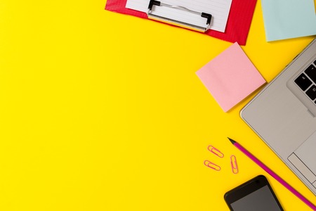 Laptop smartphone notepads clipboard sheet clips pencil colored backgroundの写真素材