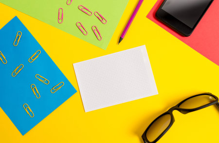 Paper sheets pencil clips smartphone eyeglasses notebook color background