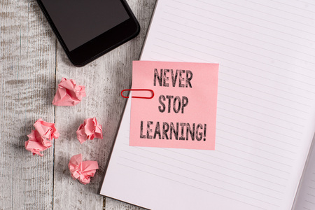 Conceptual hand writing showing Never Stop Learning. Concept meaning keep on studying gaining new knowledge or materials Notebook stationary placed above classic wooden backdropの写真素材