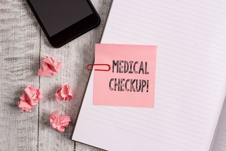 Conceptual hand writing showing Medical Checkup. Concept meaning thorough physical examination includes variety of tests Notebook stationary placed above classic wooden backdropの写真素材