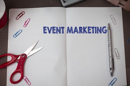 Conceptual hand writing showing Event Marketing. Concept meaning describes process of developing display to promote product Scissors and equipments math book above textured backdropの写真素材