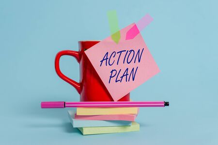 Word writing text Action Plan. Business photo showcasing proposed strategy or course of actions for certain time Cup sticky note arrow banners stacked pads pen lying pastel backgroundの写真素材