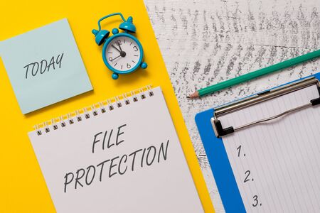 Conceptual hand writing showing File Protection. Concept meaning Preventing accidental erasing of data using storage medium Spiral notepad sheet marker alarm clock wooden backgroundの写真素材