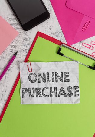 Conceptual hand writing showing Online Purchase. Concept meaning Purchases electronic commerce goods from over the Internet Clipboard sheet pencil smartphone clips notepad wooden backの写真素材