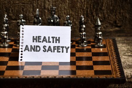 Writing note showing Health And Safety. Business concept for procedures intended to prevent accident in workplace Empty Notepad Sheet Folded in Half Chessboard Themed Chess Set Piecesの写真素材