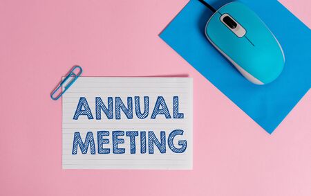Text sign showing Annual Meeting. Business photo showcasing yearly meeting of the general membership of an organization Wire electronic mouse striped blank paper sheets clip colored backgroundの写真素材