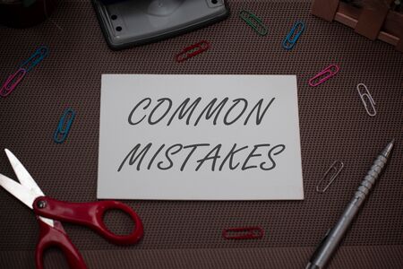 Handwriting text writing Common Mistakes. Conceptual photo actions that are often used interchangeably with error Scissors and writing equipments plus plain sheet above textured backdropの写真素材