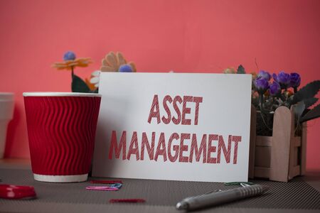Writing note showing Asset Management. Business concept for systematic process of operating and disposing of assets Flowers and writing equipments sheet above textured backdropの写真素材
