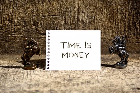 Conceptual hand writing showing Time Is Money. Concept meaning time is a valuable resource Do things as quickly as possible Two Bronze Chessmen Knights Ring Notepad Sheet Folded Halfの写真素材