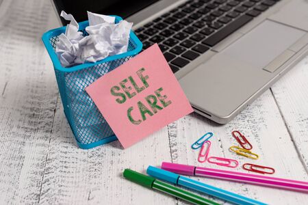 Writing note showing Self Care. Business concept for the practice of taking action to improve one s is own health Laptop sticky note waste basket crushed paper clips pens vintage tableの写真素材