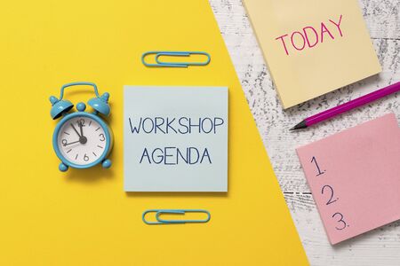 Handwriting text writing Workshop Agenda. Conceptual photo helps you to ensure that your place stays on schedule Notepads clips colored paper sheet marker alarm clock wooden backgroundの写真素材