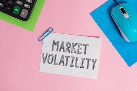 Conceptual hand writing showing Market Volatility. Concept meaning Underlying securities prices fluctuates Stability status Wire electronic mouse calculator paper colored backgroundの写真素材