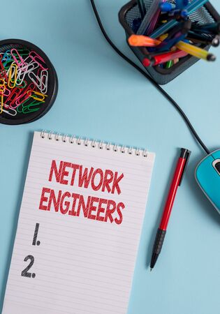 Writing note showing Network Engineers. Business concept for Technology professional Skilled in computer system Notebook and stationary with mouse above pastel backdropの写真素材