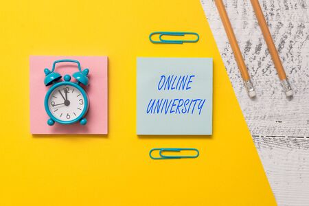 Conceptual hand writing showing Online University. Concept meaning Distance Learning Courses are taken over the internet Notepads colored paper sheet markers alarm clock wooden backgroundの写真素材
