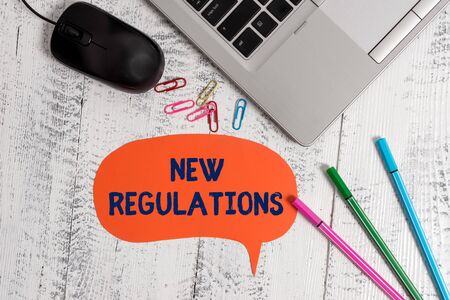 Text sign showing New Regulations. Business photo showcasing Regulation controlling the activity usually used by rules. Metallic slim laptop speech bubble colored clips pens mouse wooden vintageの写真素材