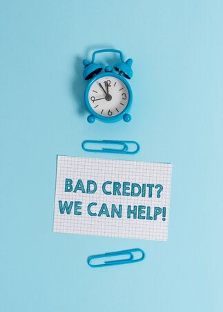 Handwriting text writing Bad Credit, We Can Help. Conceptual photo offer help to gain positive payment history Alarm clock wake up squared blank paper sheet clips colored backgroundの写真素材