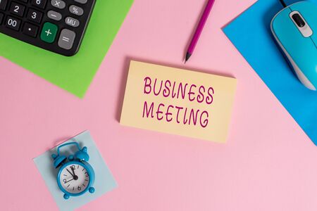 Handwriting text writing Business Meeting. Conceptual photo used discuss issues that cannot be addressed in simple way Mouse calculator sheets marker notepad alarm clock colored backgroundの写真素材