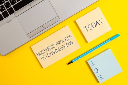 Conceptual hand writing showing Business Process Re Engineering. Concept meaning the analysis and design of workflows Silver laptop square sticky notepads marker colored backgroundの写真素材