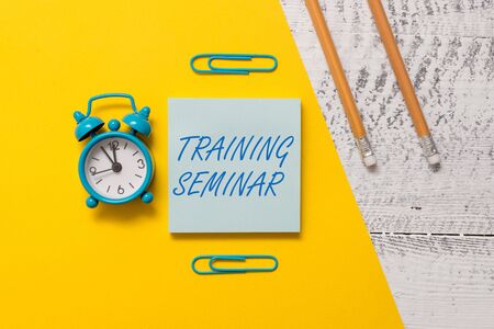 Text sign showing Training Seminar. Business photo text Academic instruction Formal presentation of a research Notepad clips colored paper sheet markers alarm clock wooden backgroundの写真素材