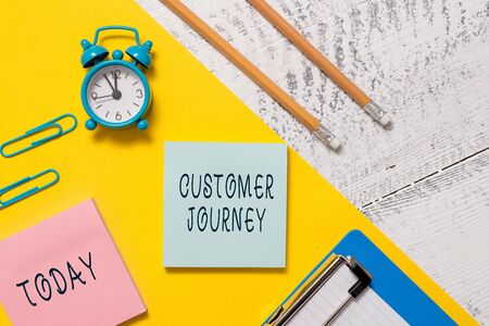 Word writing text Customer Journey. Business photo showcasing product of interaction between organization and customer Notepads clips paper sheet clipboard markers alarm clock wooden backgroundの写真素材