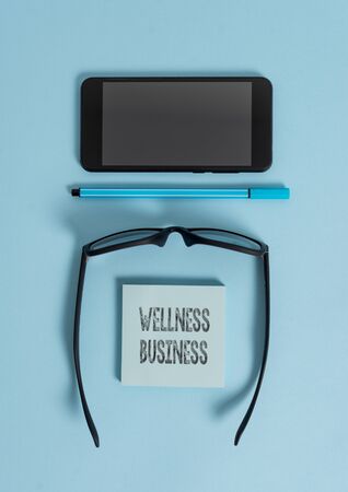 Conceptual hand writing showing Wellness Business. Concept meaning Professional venture focusing the health of mind and body Dark eyeglasses colored sticky note smartphone pastel backgroundの写真素材