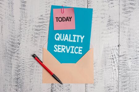 Text sign showing Quality Service. Business photo text how well delivered service conforms to clientexpectations Envelope blank sheet letter paper sticky note ballpoint wooden backgroundの写真素材