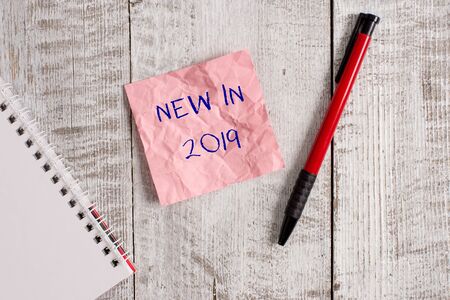 Writing note showing New In 2019. Business concept for what will be expecting or new creation for the year 2019 Wrinkle paper notebook and stationary placed on wooden backgroundの写真素材