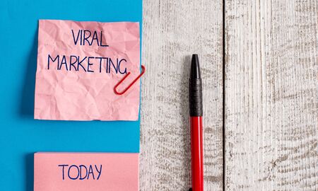 Handwriting text Viral Marketing. Conceptual photo whereby consumer encouraged share information via Internet Wrinkle paper and cardboard plus stationary placed above wooden backgroundの写真素材