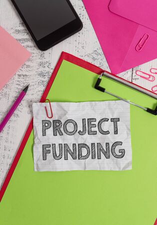 Conceptual hand writing showing Project Funding. Concept meaning paying for start up in order make it bigger and successful Clipboard sheet pencil smartphone clips notepad wooden backの写真素材